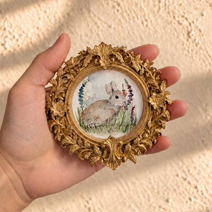 Baby bunny watercolor print in round gold baroque frame, held in hand