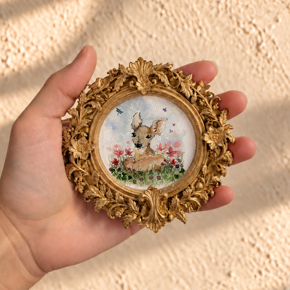 Baby fawn watercolor print in round gold baroque frame, held in hand